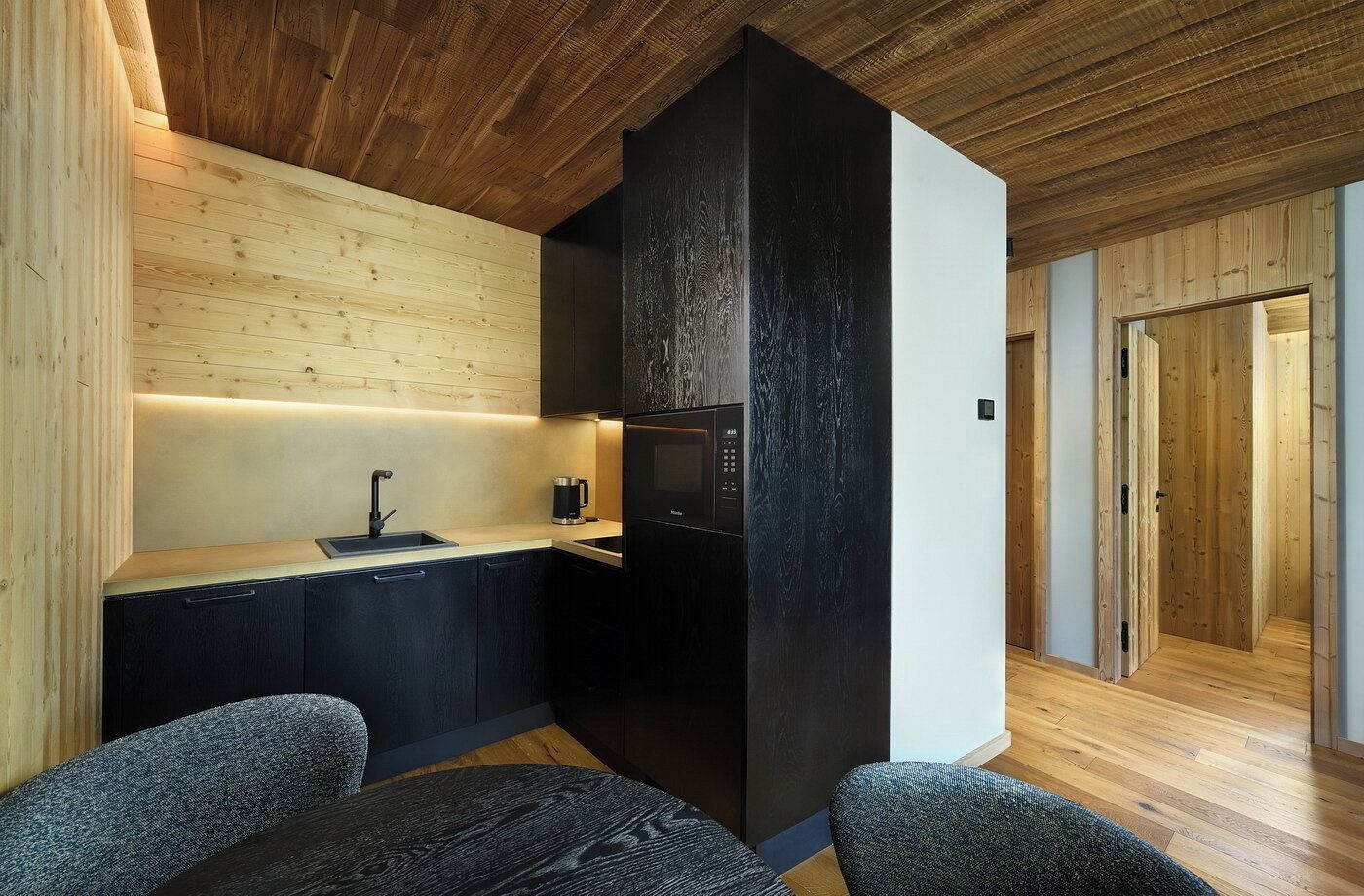 Una cocina moderna con techo de madera, refrigerador negro y encimera de madera.