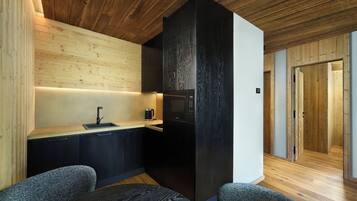 Una cocina moderna con techo de madera, refrigerador negro y encimera de madera.