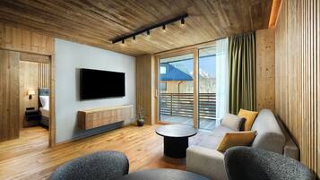 A modern interior with a wooden ceiling, a flat-screen TV mounted on the wall, a sofa, and a small round table.