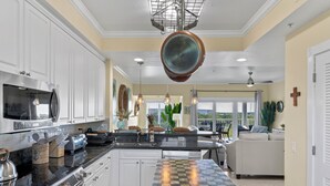 A modern kitchen with white cabinetry, stainless steel appliances, and a checkered tile floor.