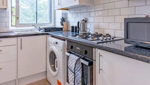 A modern kitchen with white cabinets, a built-in washing machine, a stove, and a microwave.