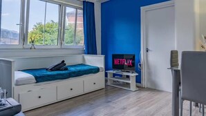 A modern room with a bed, a TV, and a dining area.