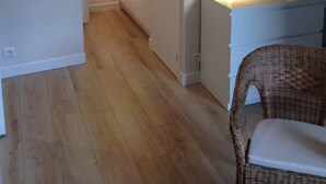 A modern apartment with a wooden floor, a kitchenette, a dining area with a wicker chair, and a small table with a lamp. - Charming 2 rooms old Lille, terrace, parking (Lille)