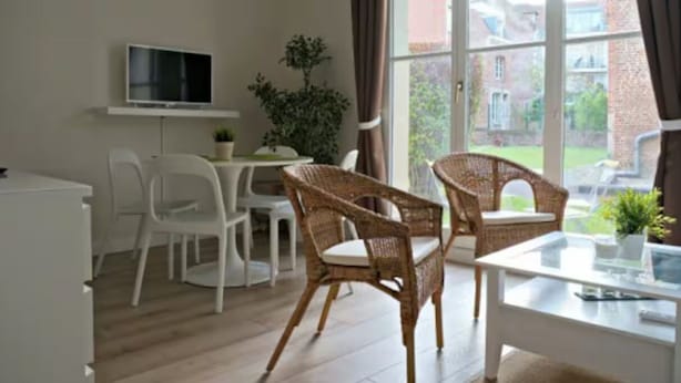 A room with a white desk, two wicker chairs, a TV on the wall, and a view of the outside. - Charming 2 rooms old Lille, terrace, parking (Lille)