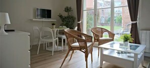 A room with a white desk, two wicker chairs, a TV on the wall, and a view of the outside. - Charming 2 rooms old Lille, terrace, parking (Lille)