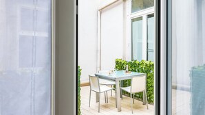 A glass table with chairs, a window, and a hedge outside. - Residenza Diaz by Wonderful Italy (Naples)