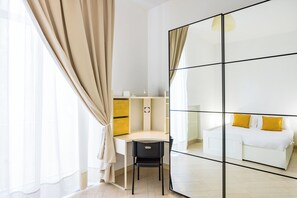 Une chambre moderne équipée d’un bureau, d’une chaise et d’un lit avec des oreillers jaunes.