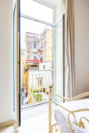 Ein Zimmer mit Bett, Fenster und Blick auf Gebäude.