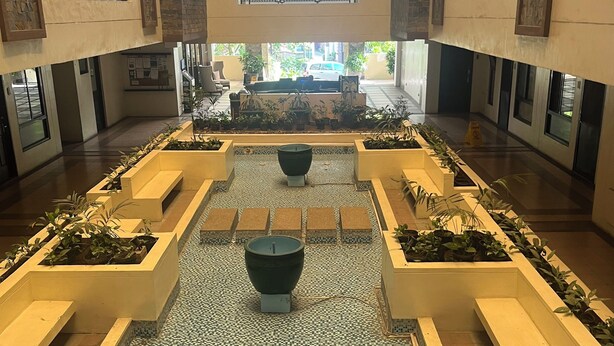 A spacious lobby with a central water feature, multiple seating areas, and a view of the street outside. - Chic 2-bedroom condo with WiFi, fitness room and Pool in vibrant Quezon City (Quezon City)