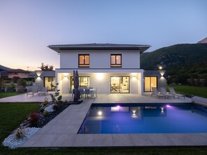 Uma casa moderna de dois andares com piscina, área de estar externa e um jardim bem cuidado.