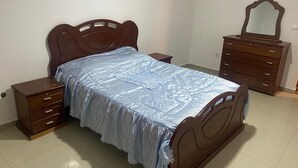 Une chambre à coucher avec un lit en bois, une table de chevet, une commode et un miroir.