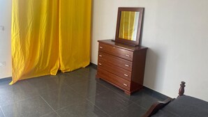 Une pièce avec une commode en bois, un miroir et des rideaux jaunes.