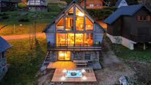 Une cabane en bois dotée d’un balcon, d’un jacuzzi et de fondations en pierre.