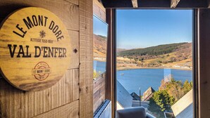 Un letrero de madera con la inscripción 'LE MONT DORE VAL D'ENFER' y 'ALTITUD 1050-1896' en una pared de edificio.