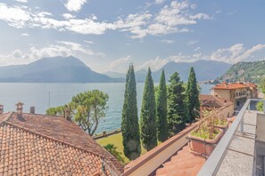 A terrace with a tiled roof overlooking a lake, cypress trees, and distant mountains. - Varenna La Dolce Vita (Varenna)
