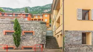 Un edificio in pietra con una scala che conduce a un edificio giallo con persiane.
