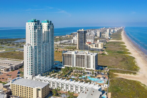 Un hôtel de grande hauteur, avec de nombreux étages, une vue sur la plage et un espace piscine.