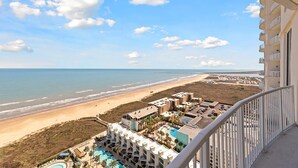 A beachfront hotel with multiple buildings, a swimming pool, and a view of the beach and ocean.