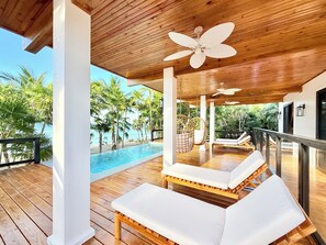 A wooden deck with a pool, white lounge chairs, and a ceiling fan. - Main House @ Pacific Pearl, Milton Bight (José Santos Guardiola)