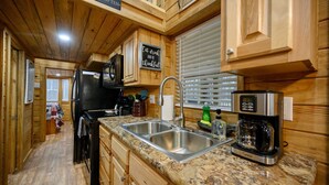 Una cocina con armarios de madera, encimera de granito, pileta de acero inoxidable y una cafetera.