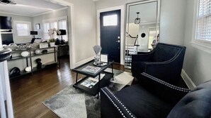 A modern living room with a black leather sofa, a coffee table, and a dining area with a glass-top table.