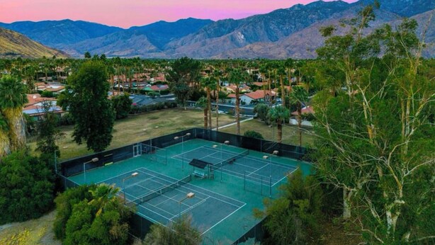 A tennis court surrounded by residential buildings and palm trees, with mountains in the background. - Tranquil 3-bedroom house in Palm Springs with WiFi and AC (Palm Springs)