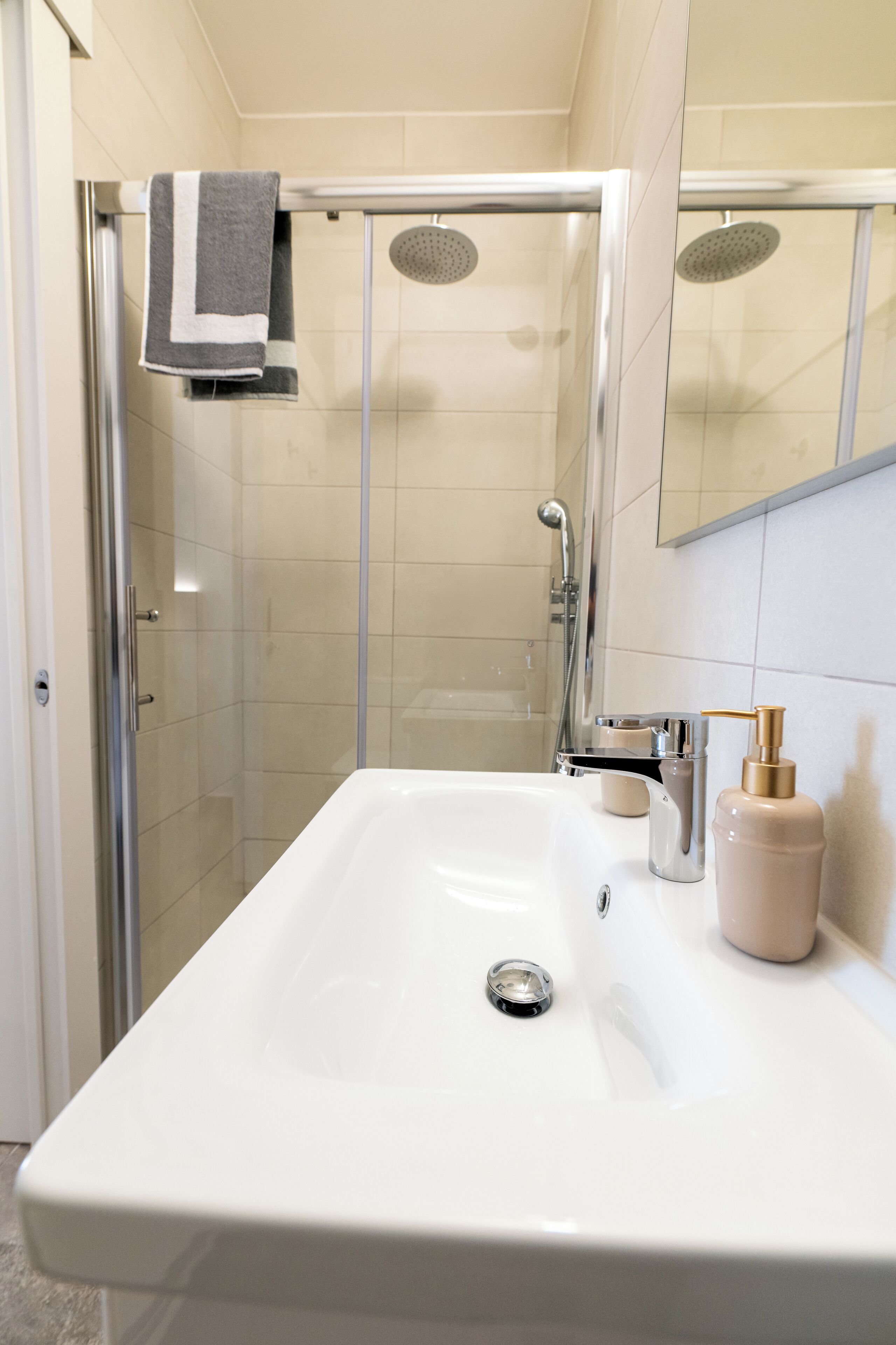 A modern bathroom with a glass-enclosed shower, a white sink, and a mirror above it.