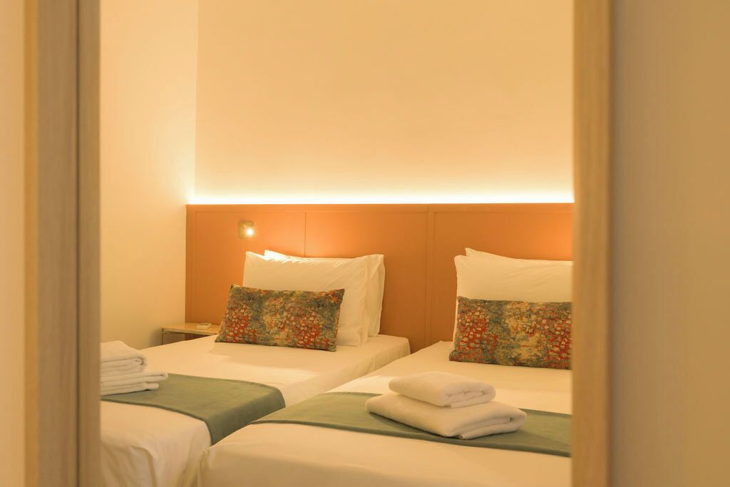 A hotel room with two beds, each with a pillow and a neatly folded towel.