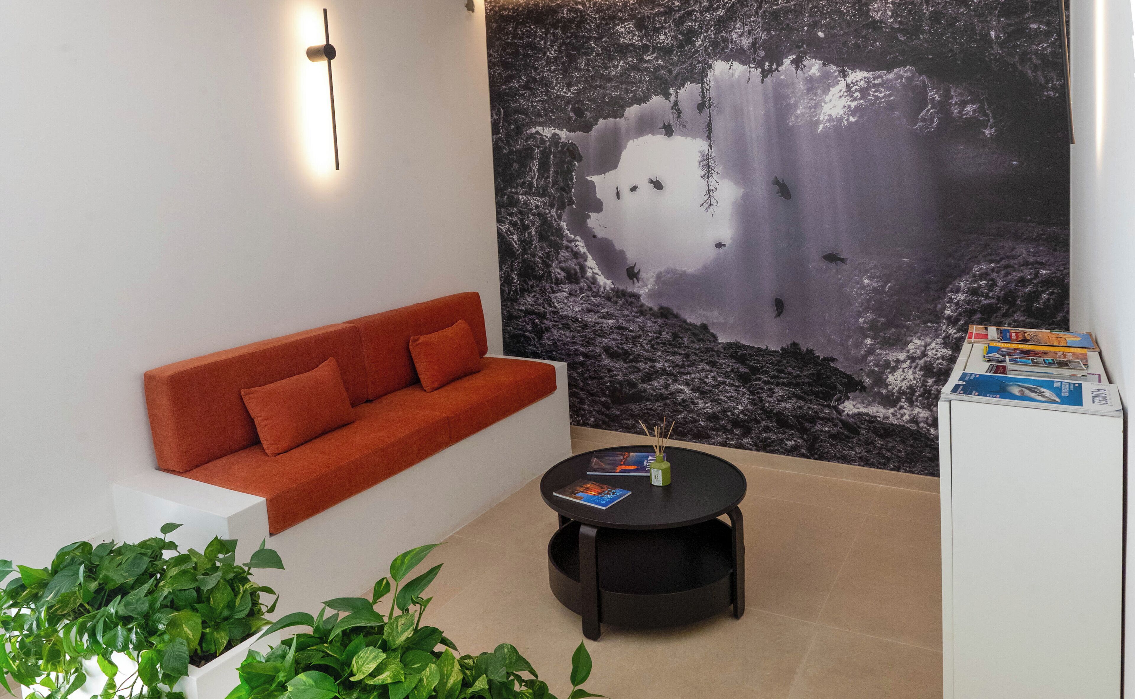 Ein modernes Wohnzimmer mit einem roten Sofa, einem runden schwarzen Tisch und einem großen Wandbild mit einem Wasserfall.