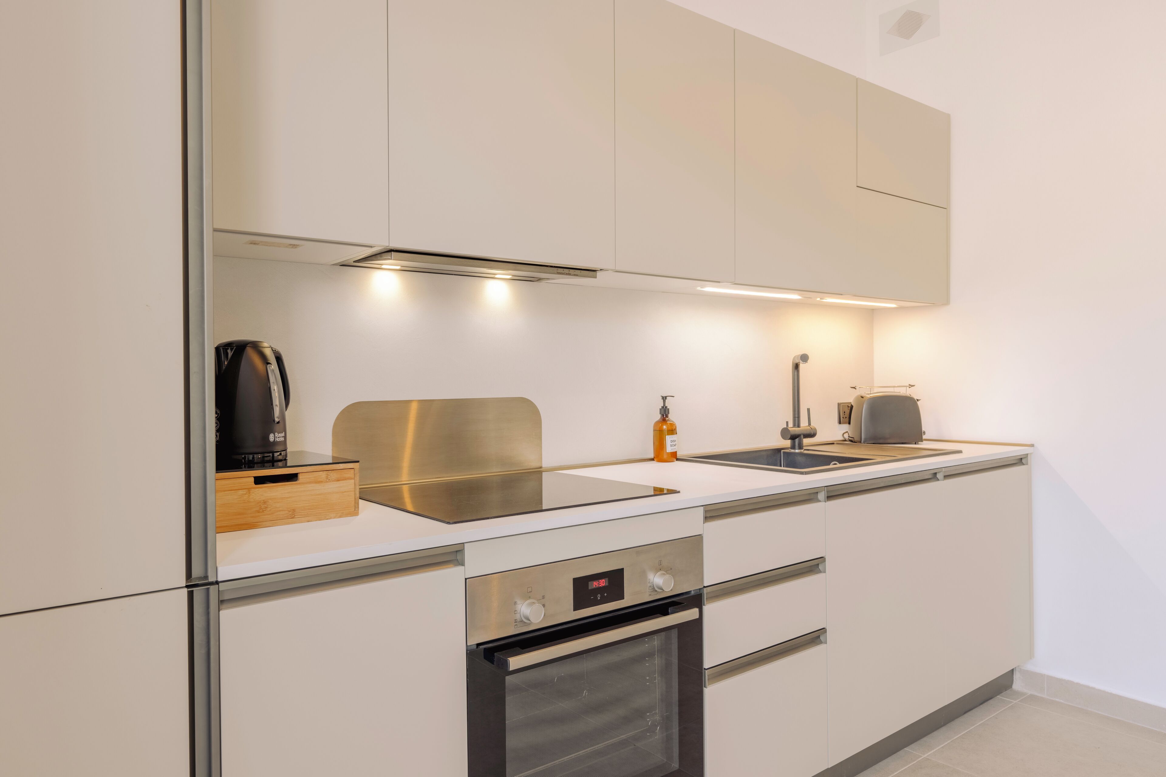 Een moderne keuken met witte kasten, roestvrijstalen apparatuur en een inbouwoven.