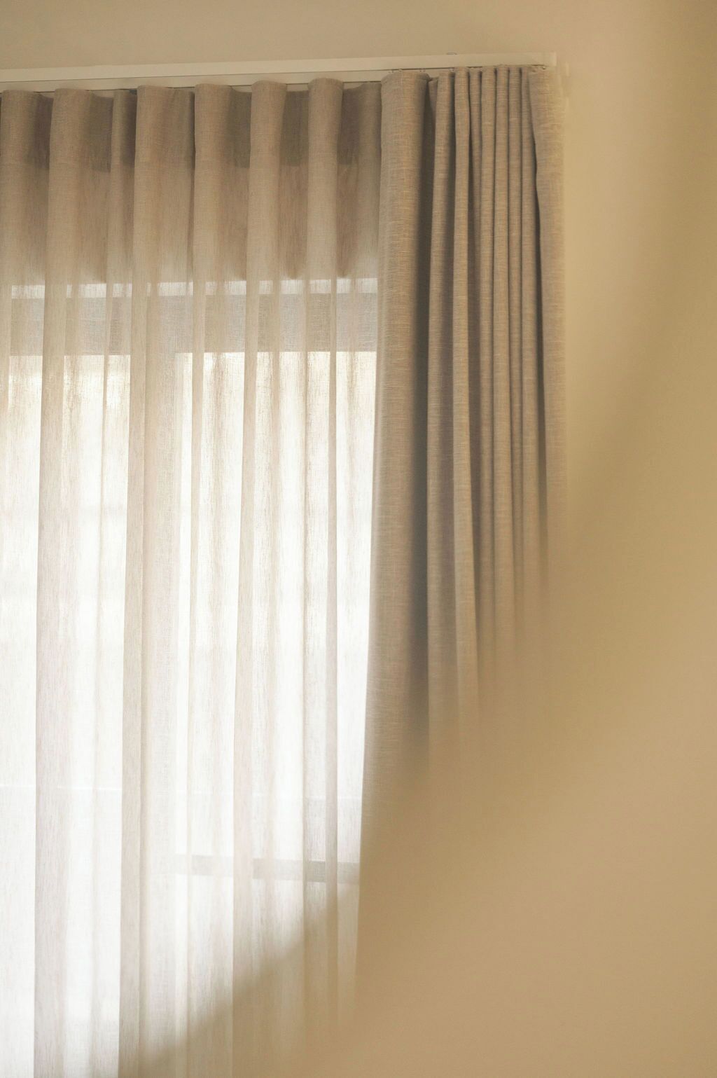 A window with sheer curtains and a solid drape.