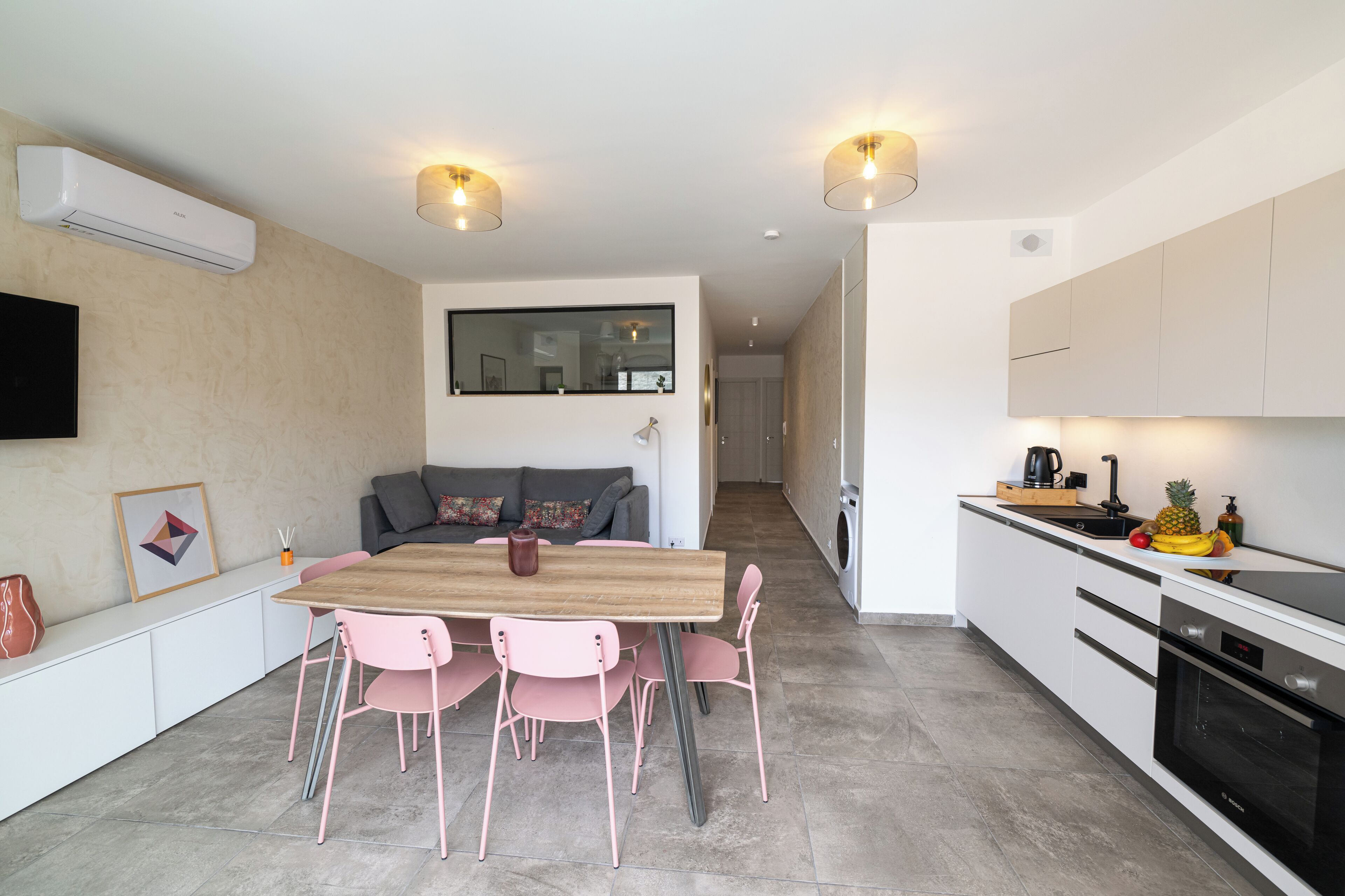 A modern kitchen with a dining area, white cabinetry, and a built-in oven.