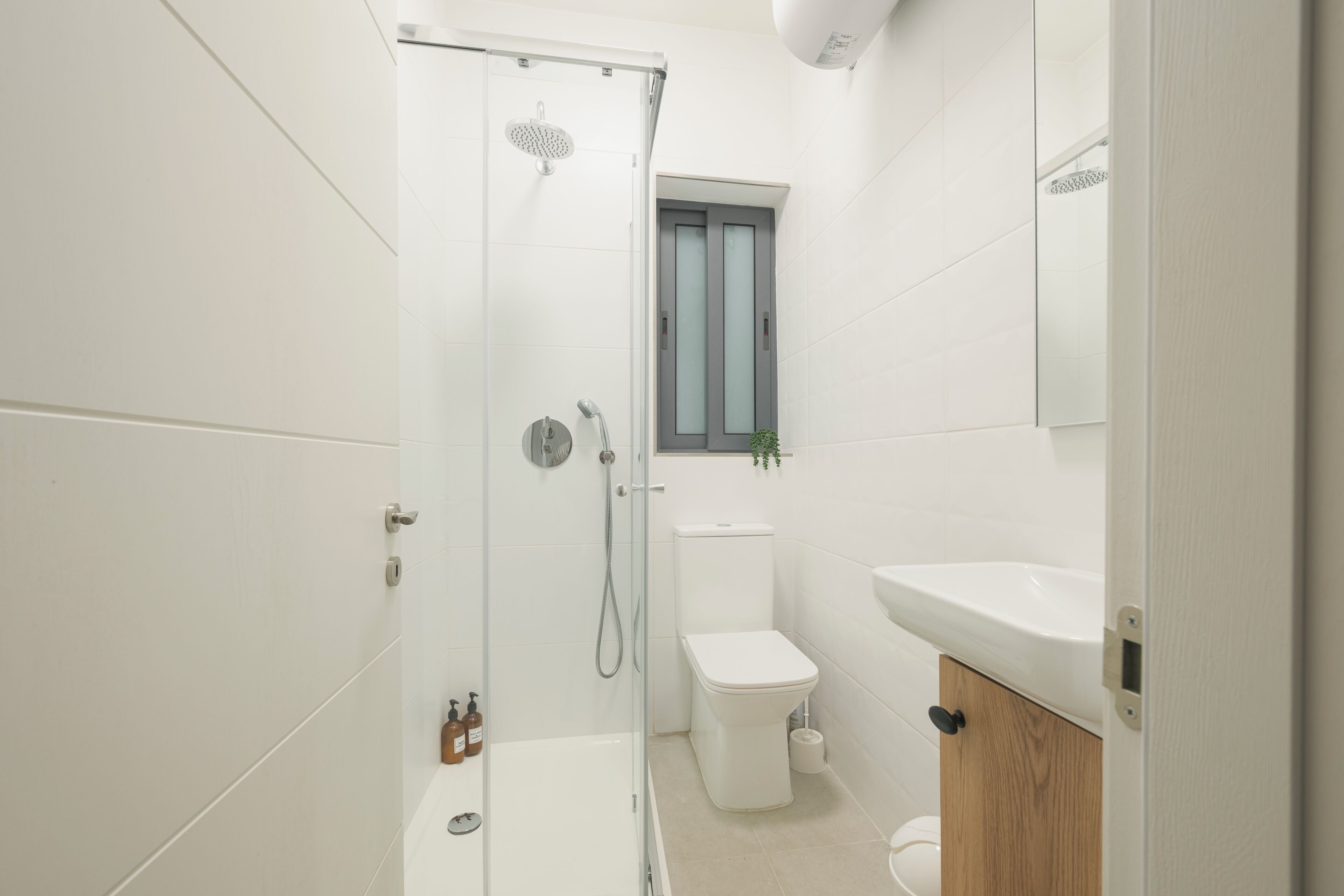 A modern bathroom with a glass shower enclosure, a toilet, and a sink.
