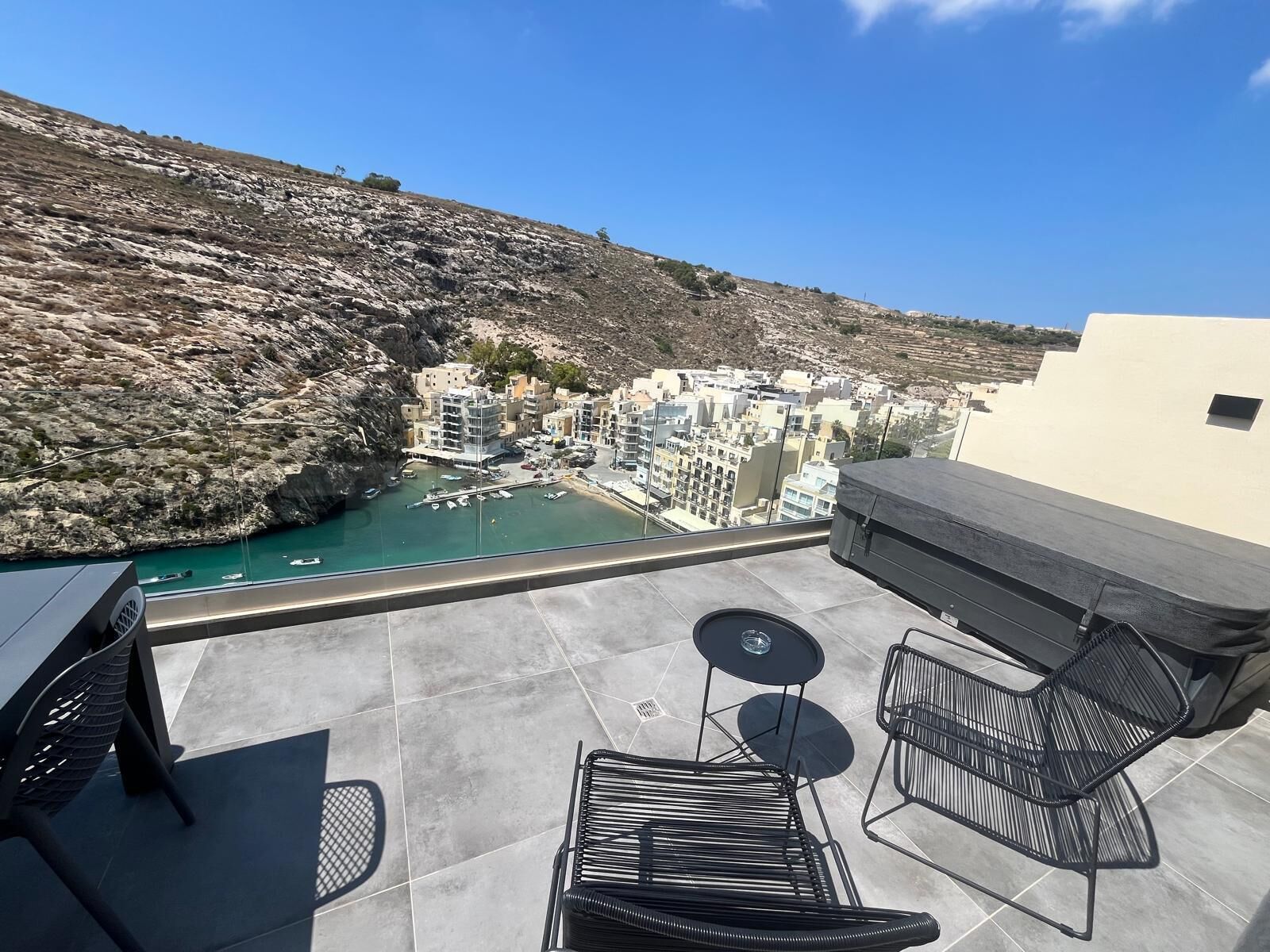 Una terraza con vistas a un pueblo costero, mobiliario exterior y zona de comedor.