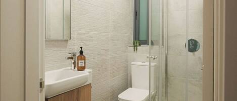 A modern bathroom with a glass shower enclosure, a wooden vanity, and a white toilet.