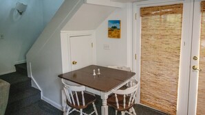 A dining area with a table and chairs, a painting on the wall, and a door with a window blind. - Gorgeous Historic Carriage House with fine furnishings and modern amenities (Atlanta)