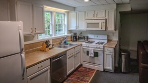 A kitchen with white cabinets, a refrigerator, a stove, a microwave, and a sink. - Gorgeous Historic Carriage House with fine furnishings and modern amenities (Atlanta)