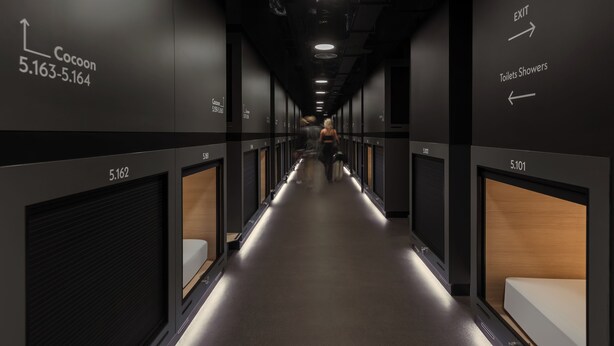 A hotel corridor with directional signs for Cocoon and toilets, and room numbers 5.162 and 5.101. - Zedwell Capsule Hotel, Piccadilly Circus (London)