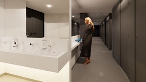 Un baño de hotel moderno con un espejo grande, un lavabo blanco y un secador de pelo en la encimera.