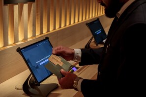 Une personne utilise une tablette sur un comptoir d’accueil, avec un mur en panneaux de bois en arrière-plan.