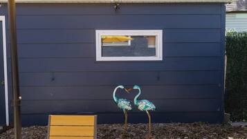 A blue house with a window, a bench, and two decorative bird figures.