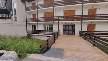 Un immeuble à plusieurs étages doté d’une terrasse en bois menant à l’entrée, sur laquelle on peut lire l’inscription « Le Roc Noir ».