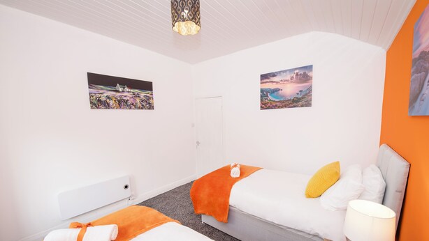 Et hotelværelse med to senge, en hvid dør og to billeder i rammer på væggene.