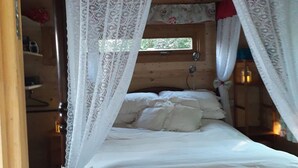 Una cama con dosel, cabecera de madera y un ventanal pequeño.