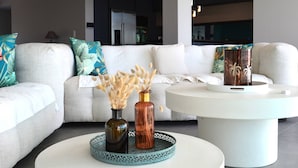A modern living room with a white sofa, a round coffee table, and decorative vases. - Villa OLYMPE – 4 Bedrooms, Pool, Panoramic Sea View (Pietrosella)