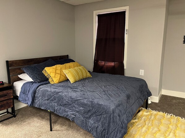 A bedroom with a bed, a nightstand, a dresser, and a door with a curtain. - Private Suite w/ Private Access in lovely Lee's Summit with WiFi, fitness room (Lee's Summit)
