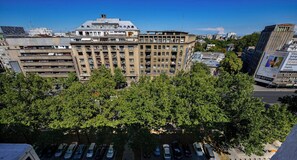 A multi-story building with a central courtyard, surrounded by trees and parked cars. - Blue Moon - One Bedroom - Romana Square (Bucharest)