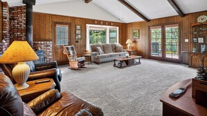 A spacious living room with a fireplace, leather furniture, and a ceiling fan. - Amazing Views, Secluded property, 2025 Remodeled, Near Yosemite & Amenities (Oakhurst)