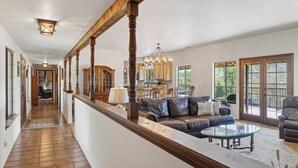 A spacious living area with a leather sofa, a glass coffee table, and a wooden railing overlooking a deck. - Amazing Views, Secluded property, 2025 Remodeled, Near Yosemite & Amenities (Oakhurst)