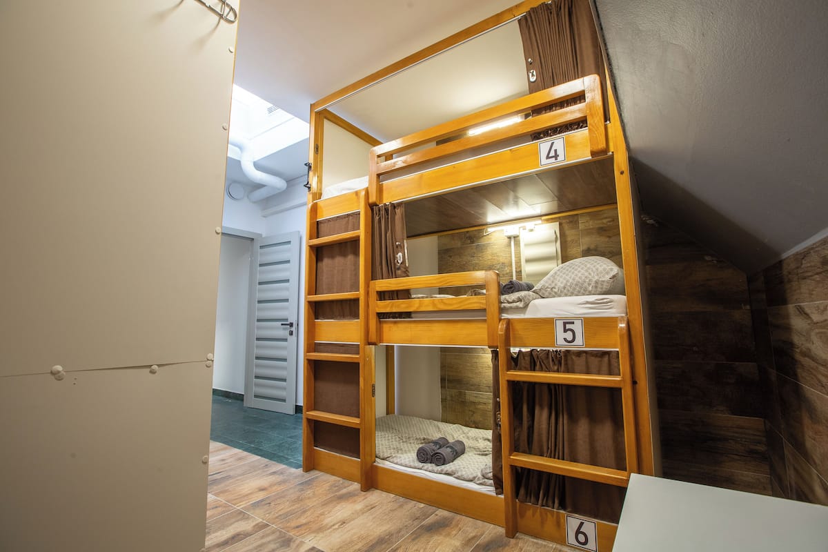 A bunk bed with numbers 4, 5, and 6, wooden railings, and a small window.